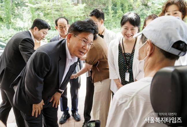 박강수 마포구청장이 휠체어를 탄 어르신의 안부를 살피고 있다.