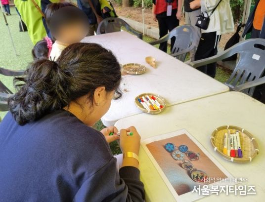 지난해 진행한 유아숲 페스티벌에서 아이와 부모가 함께 나무에 그림을 그리고 있다.