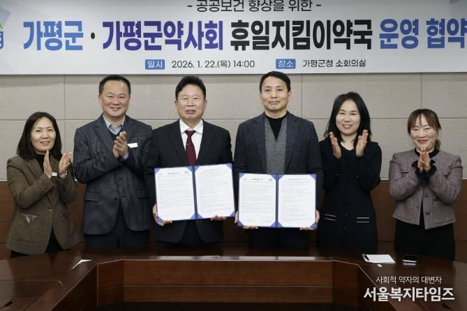 서태원 가평군수(사진 왼쪽에서 세번째)와 안병현 가평군약사회 회장(〃 네번째) 등이 22일 휴일지킴이약국 운영 협약식 후 협약서를 보이며 기념촬영을 하고 있다.